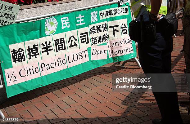 Policeman stands by a banner set up by protestors outside a Citic Pacific Ltd. Shareholders meeting in Hong Kong, China, on Friday, Dec. 19, 2008....