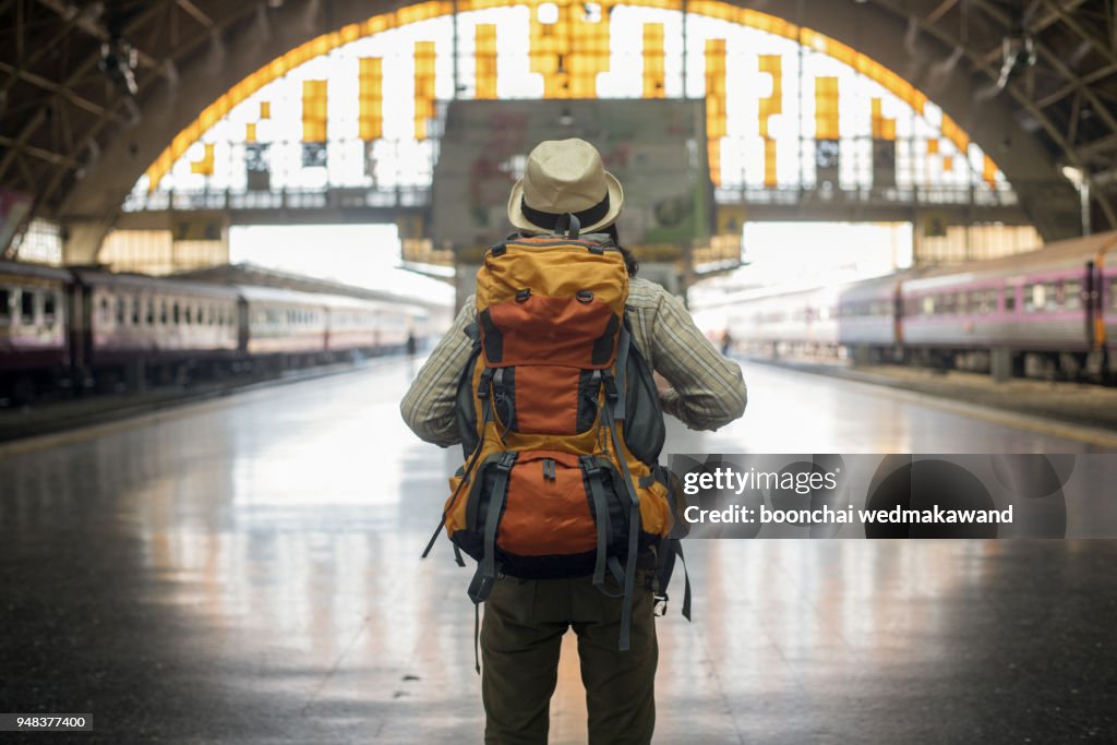 Traveler man waits train on railway platform.