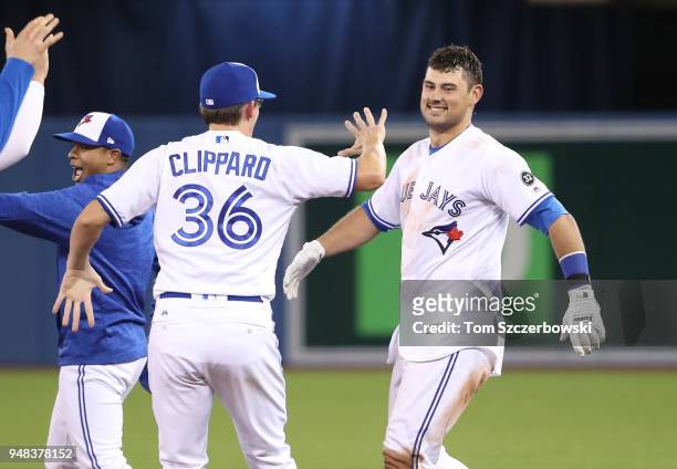 Luke Maile of the Toronto Blue Jays is congratulated on his game-winning RBI single by Tyler Clippard and teammates in the tenth inning during MLB...