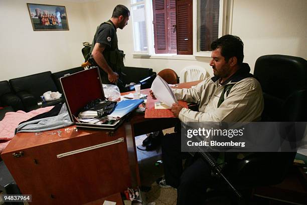 An unidentified gunman collects documents from an office belonging to the pro-government Future movement after it was occupied by pro-Syrian gunmen...