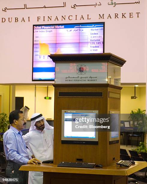 Investors check their stocks while on the floor at the Dubai Financial Market, at the Dubai World Trade Centre, in Dubai, United Arab Emirates, on...