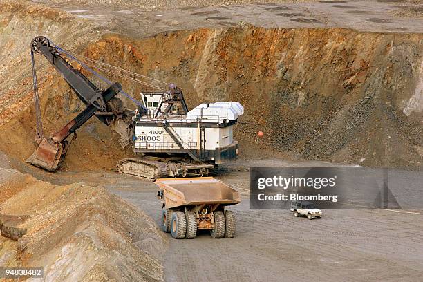 Newmont Nusa Tenggara vehicle, right, is dwarfed by a 240-tonne-capacity haul truck waiting for its next load of ore from a giant electric shovel in...