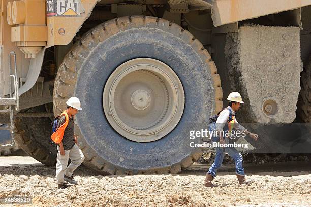 Newmont Nusa Tenggara workers walk past a 240-tonne-capacity haul truck parked on the edge of the Batu Hijau copper mining pit on the southwestern...