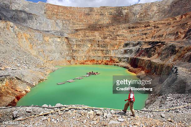 Newmont Nusa Tenggara worker walks past a lake formed at the bottom of the company's massive Batu Hijau copper mining pit on the southwestern tip of...