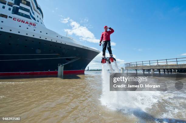 Jay St John flies close to Queen Mary 2 on July 05, 2015 in Liverpool, England. Champion flyboarder Jay St John donned a Cunard Bell Boy's uniform to...