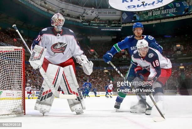 Michael Del Zotto of the Vancouver Canucks and Joonas Korpisalo and Pierre-Luc Dubois of the Columbus Blue Jackets walks a rebound during their NHL...