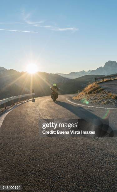 man on a motorcycle on a mountain road at sunset - crash barrier stock pictures, royalty-free photos & images