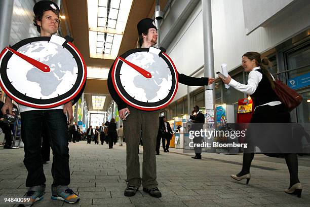 Eirek Swensen, left, and Frikk Nesja, center, dressed as clocks, hand out flyers in a demonstration outside the main plenary hall where international...