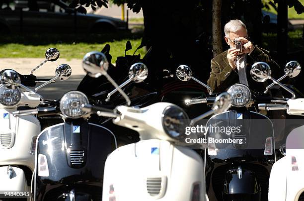 Pedestrian takes a picture of the new Vespa GTS300 scooter as they sit in Milan, Italy, on Tuesday, May 6, 2008. Piaggio & C. SpA, maker of the Vespa...