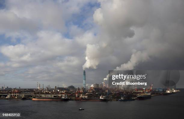 Emissions rise from chimneys as bulk carrier ships sit moored at the Nippon Steel & Sumitomo Metal Corp. Plant in Kashima, Ibaraki, Japan, on...