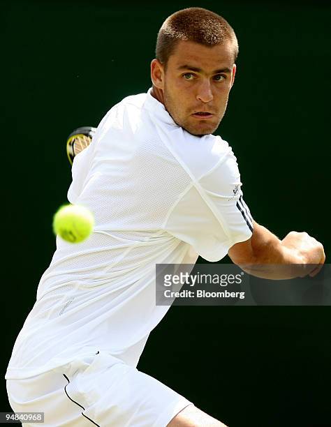 Mikhail Youzhny of Russia makes a return to Stefano Galvani of Italy, unseen, in their match at the Wimbledon tennis championships in southwest...