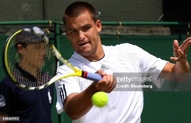 Mikhail Youzhny of Russia makes a return to Stefano Galvani of Italy, unseen, in their match at the Wimbledon tennis championships in southwest...