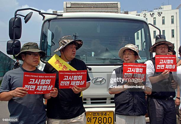 Labor union members protest in front of a truck prior to the lifting of a ban against imports of U.S. Beef in Yongin, South Korea, on Thursday, June...