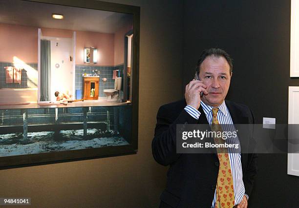 Art dealer Roland Augustine, standing next to a photograph by Gregory Crewdson, speaks on his mobile phone from the Luhring Augustine booth at the...