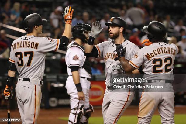 Brandon Belt of the San Francisco Giants high fives Kelby Tomlinson and Andrew McCutchen after hitting a two-run home run against the Arizona...