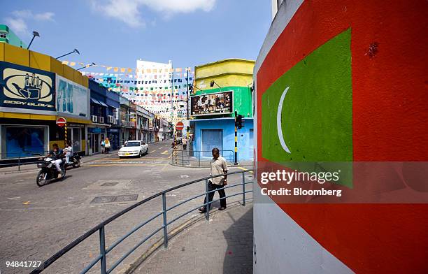 People walk past the Maldivian flag painted on a wall in Male, the Maldives, on Sunday, Dec. 7, 2008. Island countries from Grenada in the Caribbean...