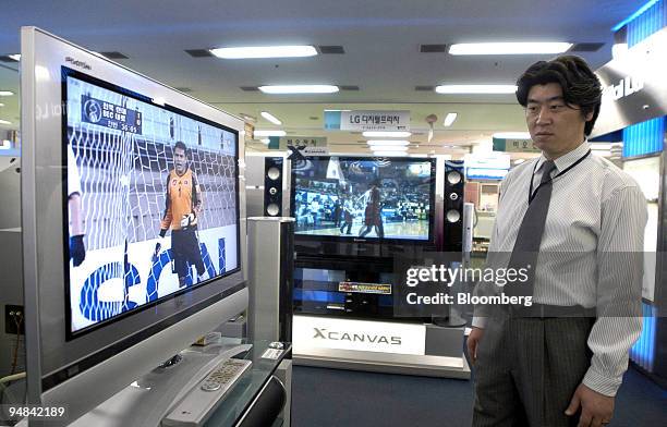 Sales clerk looks at an LG Electronics Inc.'s LCD TV monitor at a shop in Seoul Wednesday, April 21, 2004. The world's third-biggest maker of plasma...