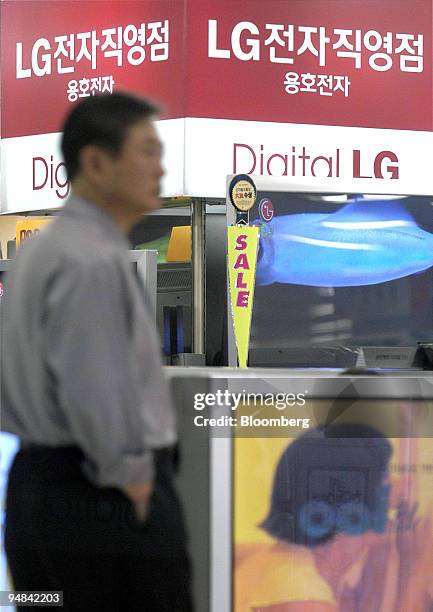 Sales clerk waits for customers next to LG Electronics Inc.'s LCD TV monitor at a shop in Seoul Wednesday, April 21, 2004.