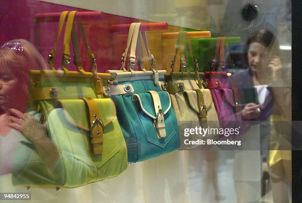 Coach Inc. Bags are seen in a window, and women are seen in the reflection as they walk past a Coach Inc. Store in New York on Tuesday, April 20,...