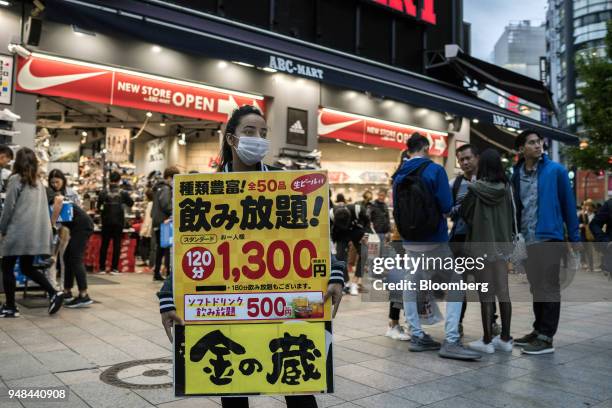 Woman holds an advertisement for a local restaurant in the Shinjuku District of Tokyo, Japan, on Saturday, April 14, 2018. Japan's headline inflation...