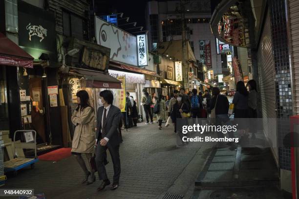 People walk through a street lined with bars and restaurants in the Kichijoji neighborhood in Tokyo, Japan, on Monday, April 16, 2018. Japan's...