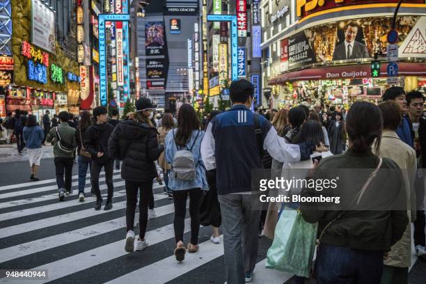 People walk past stores in the Shinjuku District of Tokyo, Japan, on Saturday, April 14, 2018. Japan's headline inflation measure is expected to rise...