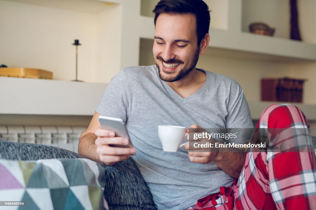 Man leest sms-berichten terwijl u geniet van koffie thuis