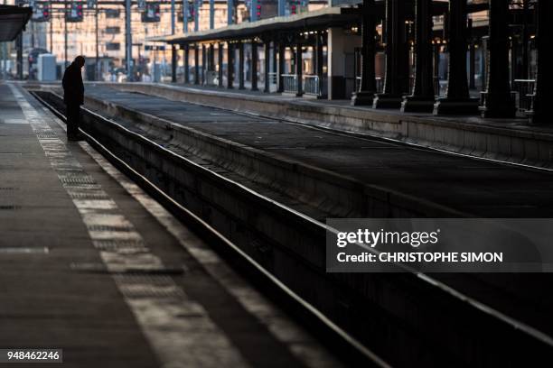 Commuter stands on a platform at the Gare de Lyon railway station, on April 19, 2018 in Paris, on the second day of a two-day stoppage on the French...