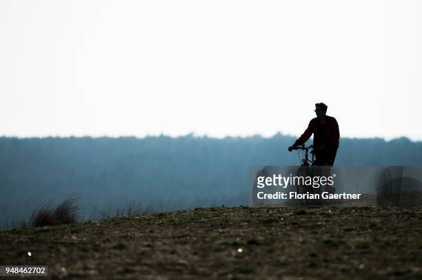 Man is standing next to a bike on the Drachenberg in Berlin on April 08, 2018 in Berlin, Germany. The Teufelsberg or Drachenberg is a hill arised of...