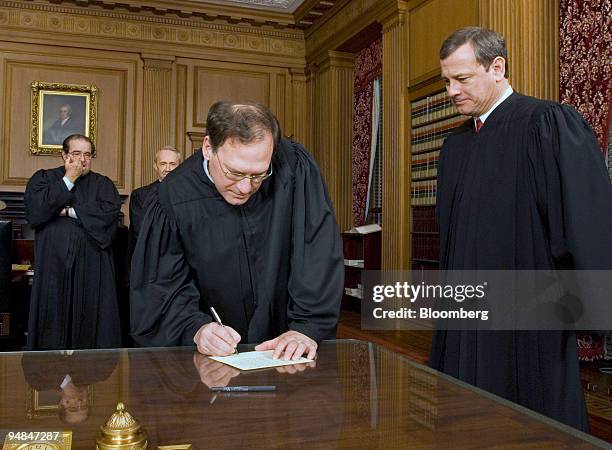 Justice Samuel A. Alito, Jr. Signs his oath card in the Justices' Conference Room as Chief Justice John G. Roberts, Jr., right, looks on with...