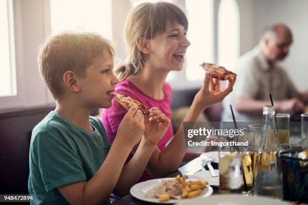kids enjoying tasty pizza in restaurant - pizza restaurant stock pictures, royalty-free photos & images