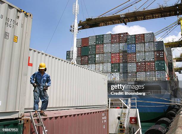 Dock worker prepares to climb down from atop containers stacked on a vessel berthed in PSA Corp.'s Tanjong Pagar Container Terminal port in Singapore...