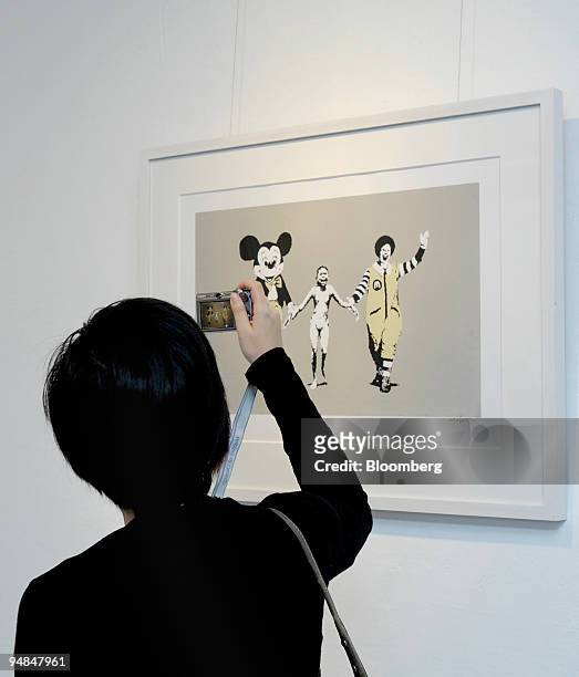 Visitor takes a photograph of British artist Banksy's 2004 screenprint "Napalm," on display as part of the "Love Art" exhibition at the Pao Galleries...