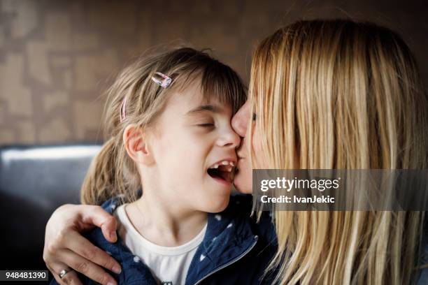 mother kissing daughter with impaired vision - cerebral palsy stock pictures, royalty-free photos & images