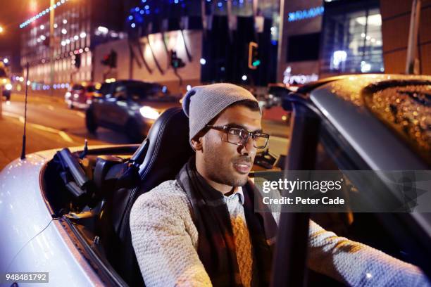 young man driving car through city at night - convertible top stock pictures, royalty-free photos & images