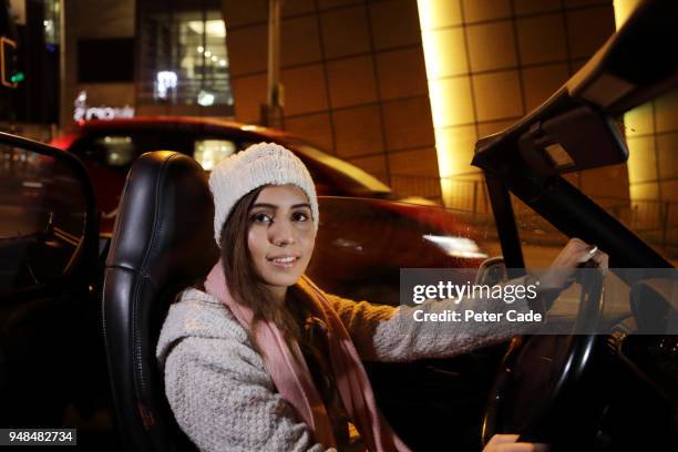 young woman driving car through city at night - convertible top stock pictures, royalty-free photos & images