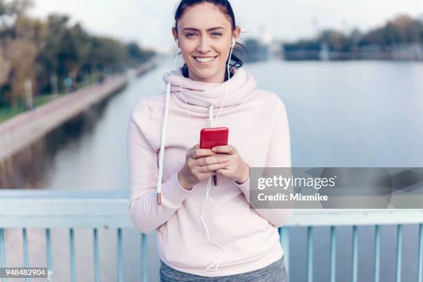 sportieve vrouw rustend op de brug en sms op haar telefoon - 2017 common good forum stockfoto's en -beelden