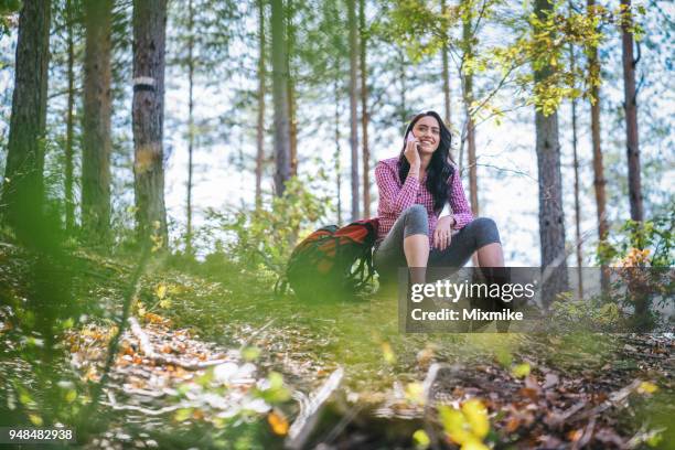 young woman talking on the phone while resting on the hill - 2017 common good forum stock pictures, royalty-free photos & images