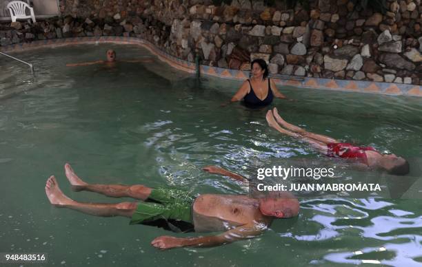 By Oscar Laski People float in pool filled with salt water from Epecuen lagoon at the spa in a hotel of Carhue, on May 4 near Lago Epecuen village,...