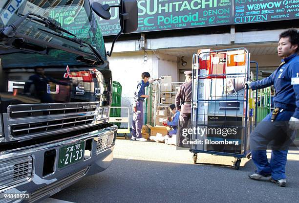 Worker prepares to load a truck with boxes in front of a Mitsubishi Fuso Fighter truck in Tokyo on Wednesday, December 8, 2004. DaimlerChrysler AG,...