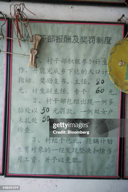 Poster stating rewards and fines for officials in meeting family-planning goals hangs at a village office near Xi'an, China, on Thursday, March 6,...