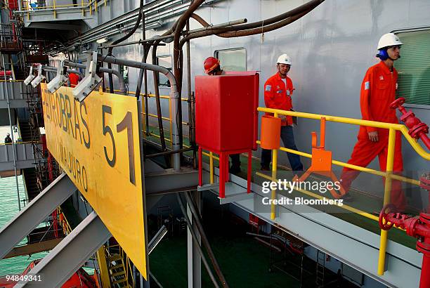 Rig workers walk past the Petroleo Brasileiro SA P-51 oil platform at the Keppel-Fels Shipyard in Angra dos Reis, Rio de Janeiro, Brazil, on...