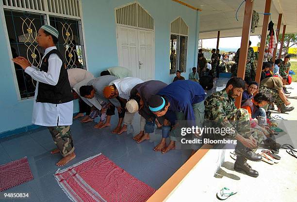 Muslims pray as soldiers and rescue volunteers put on their shoes in a small mosque at the military airport in Banda Aceh, Indonesia on Friday,...