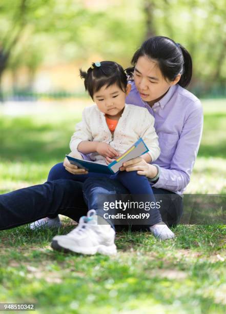 mère et fille de lecture - fille lire gazon photos et images de collection