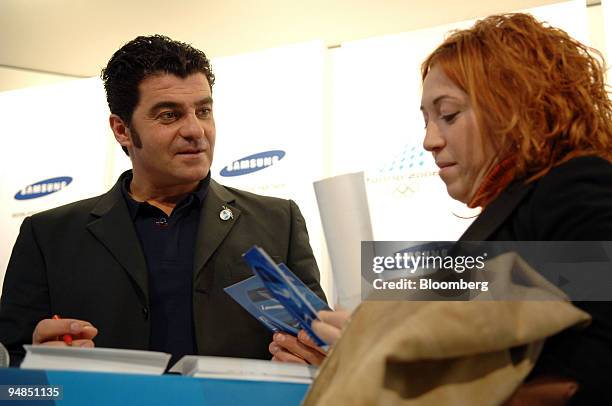 Alberto Tomba, Italian multi gold medal-winning slalom skier, signs autographs for a fan at the 2006 Olympic Games in Turin, Italy, Tuesday, February...