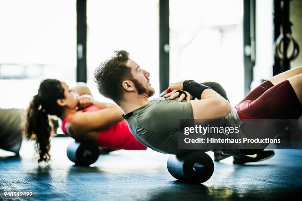 gym goers performing floor exercises together - trainingsraum freizeiteinrichtung stock-fotos und bilder