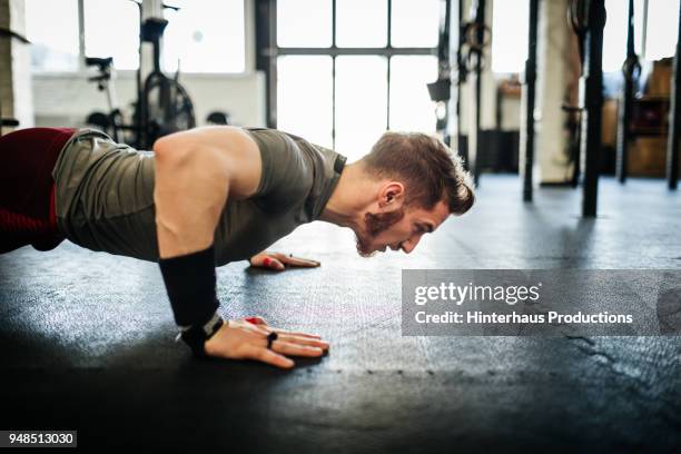man doing push ups at gym - flexiones fotografías e imágenes de stock