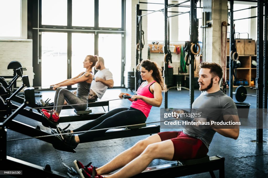 Fitness Enthusiasts Exercising Using Rowing Machines