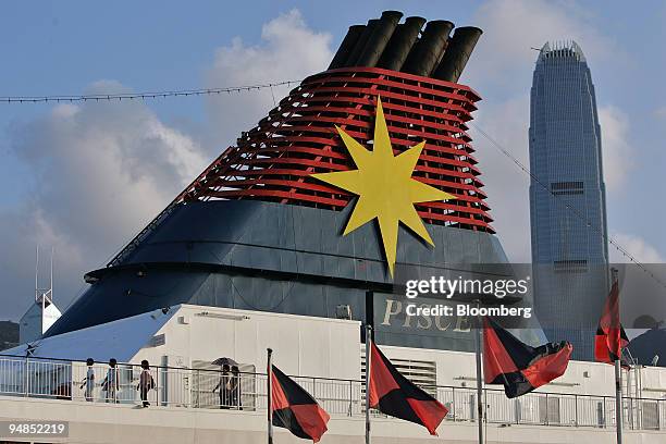 Passengers walk below the funnel aboard Star Cruises Ltd.'s Pisces cruise ship while berthed in Hong Kong, China July 11, 2005. The company, which...
