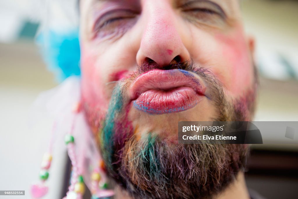 Puckering man wearing lipstick and multicoloured chalk through beard